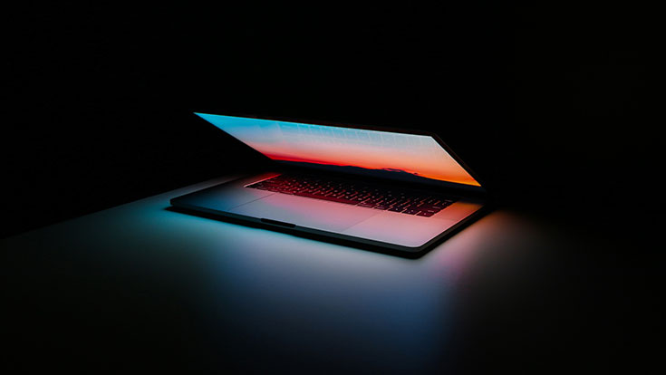 A laptop semi-open on a dark background